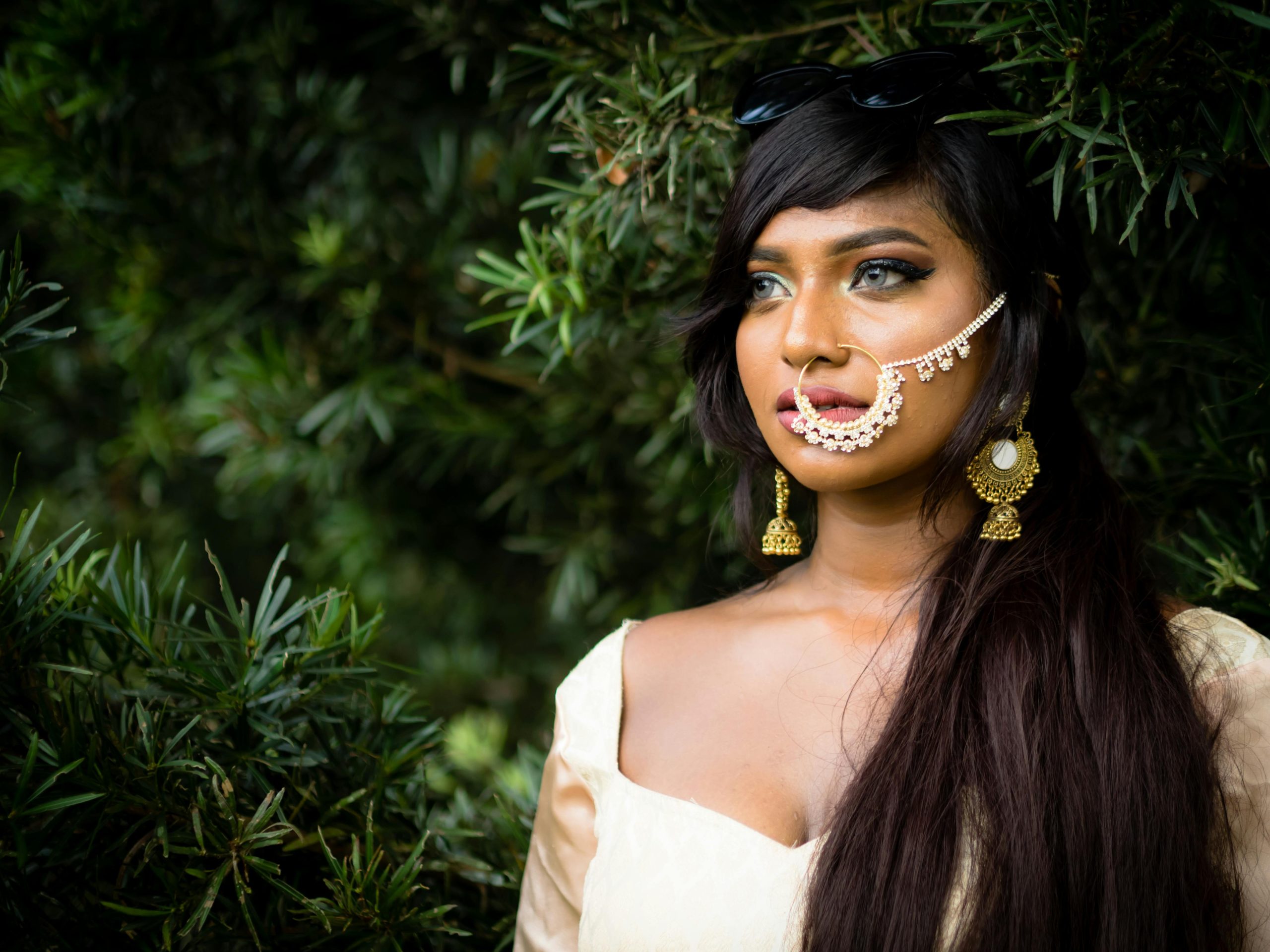 Portrait of a woman with intricate jewelry and traditional attire in a natural setting.